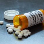 Prescription bottle with pills spilled on table.