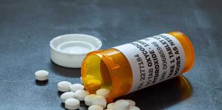 Prescription bottle with pills spilled on table.