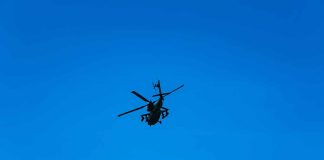 Silhouette of a helicopter against clear blue sky.