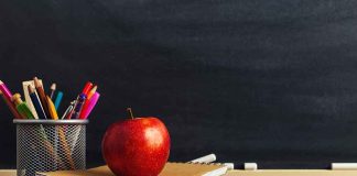 Apple on books with pencils beside a chalkboard.