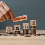 Hand holding inflation sign over stacked coins