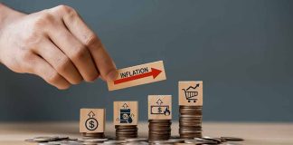 Hand holding inflation sign over stacked coins
