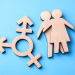 Wooden figures and transgender symbol on blue background