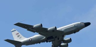 Military aircraft flying in clear blue sky.