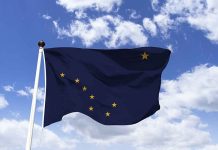 Alaska state flag flying against a blue sky.