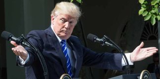 Man gesturing at two podiums outdoors.