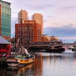 Historic ship docked near modern buildings at sunset.