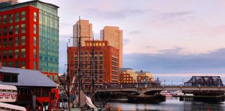 Historic ship docked near modern buildings at sunset.