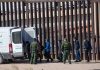 Border patrol agents detaining people near a fence
