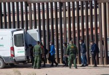 Border patrol agents detaining people near a fence