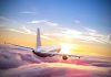 Airplane flying above the clouds at sunset