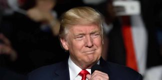 Person in suit holding a microphone speaking indoors