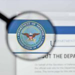 Magnifying glass over Department of Defense logo.