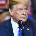 Man speaking at a rally in blue suit