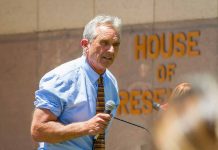 Man speaking into microphone outside building