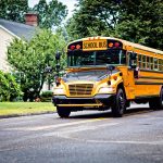 Yellow school bus driving on suburban road