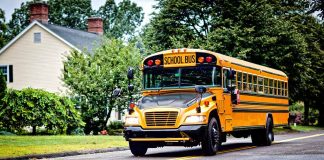 Yellow school bus driving on suburban road