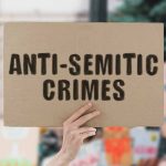 Hand holding sign saying AntiSemitic Crimes