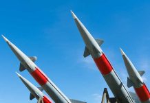 Four missiles pointing upwards under blue sky.