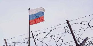 Barbed wire fence with a Russian flag above