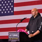 Senator Fetterman’s Stand Against Proposed Cuts and Push for Education Funding Person speaking at podium with American flag backdrop