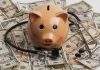 Piggy bank stethoscope money scattered underneath currency bills