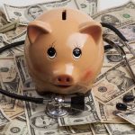 Piggy bank stethoscope money scattered underneath currency bills