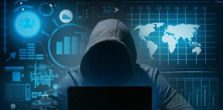 Hacker in hoodie using laptop with digital graphs