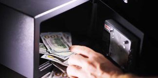 Hand putting cash into a safe.