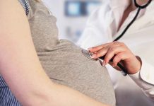 Doctor uses stethoscope on pregnant woman's belly.