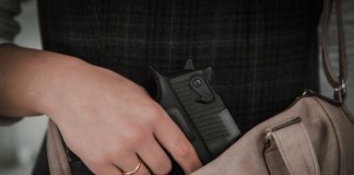 Hand placing handgun into beige handbag