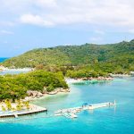 Tropical beach with docks and lush green hills