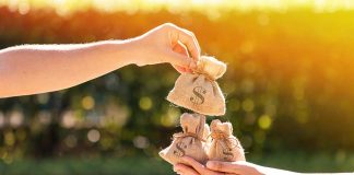 Hands exchanging small burlap bags with dollar signs