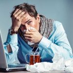 H5N1 OUTBREAK Surges — U.S. Eyes Urgent Action Man with tissue feeling unwell at laptop desk
