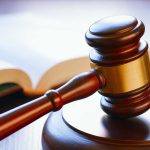 Gavel resting on sounding block beside open book