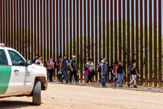 2333258557 featured image People walking beside tall fence and border patrol vehicle