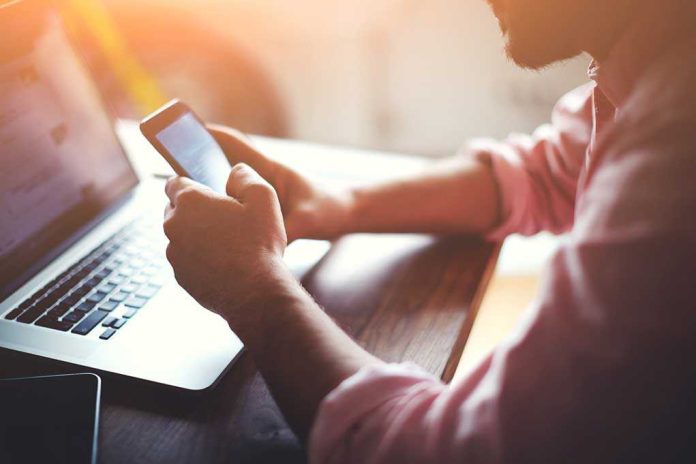 268450493 featured image Person using smartphone while seated at a laptop