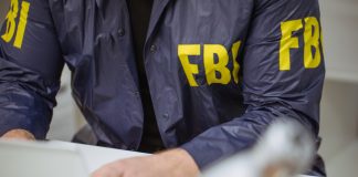 Person wearing FBI jacket using a laptop