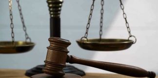 Gavel and scales of justice on wooden table.