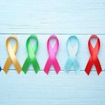 Colorful awareness ribbons on light wooden background