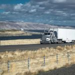 Truck driving on rural highway near river and mountains