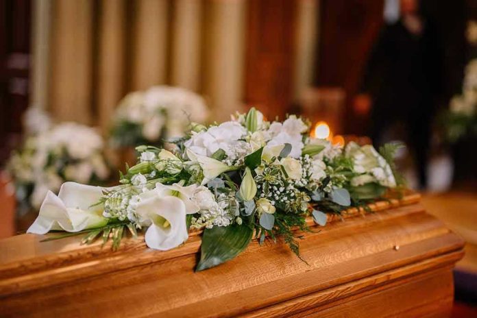 2288021055 Flower arrangement on a wooden casket at a funeral
