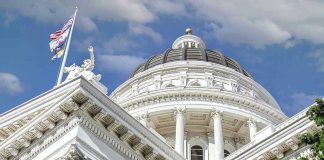 Capitol building dome and flags under a blue sky