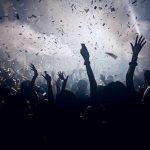 Crowd celebrating under confetti and bright lights