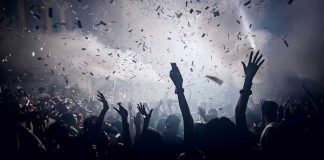 Crowd celebrating under confetti and bright lights