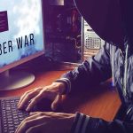 Hacker typing at desk with Cyber War screen