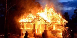 House engulfed in flames with firefighters present
