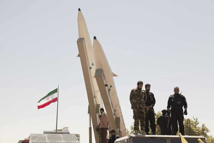 681421708 Military personnel beside missiles and Iranian flag