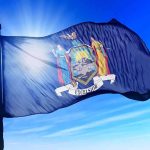 New York state flag waving against a blue sky