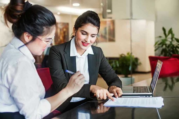 Two women discussing papers at a laptop